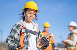 A young student wearing protective equipment in a construction site.