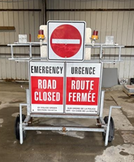 Mobile road sign displaying the messages “Road Closed” and “Route Fermée,” topped with a no‑entry symbol.